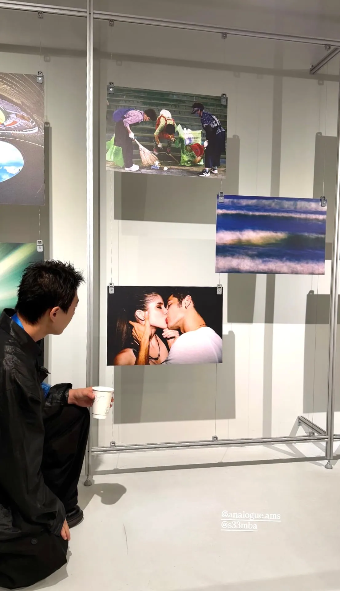 Visitor looking at photo prints hanging in the gallery room, Analogue store Zeedijk