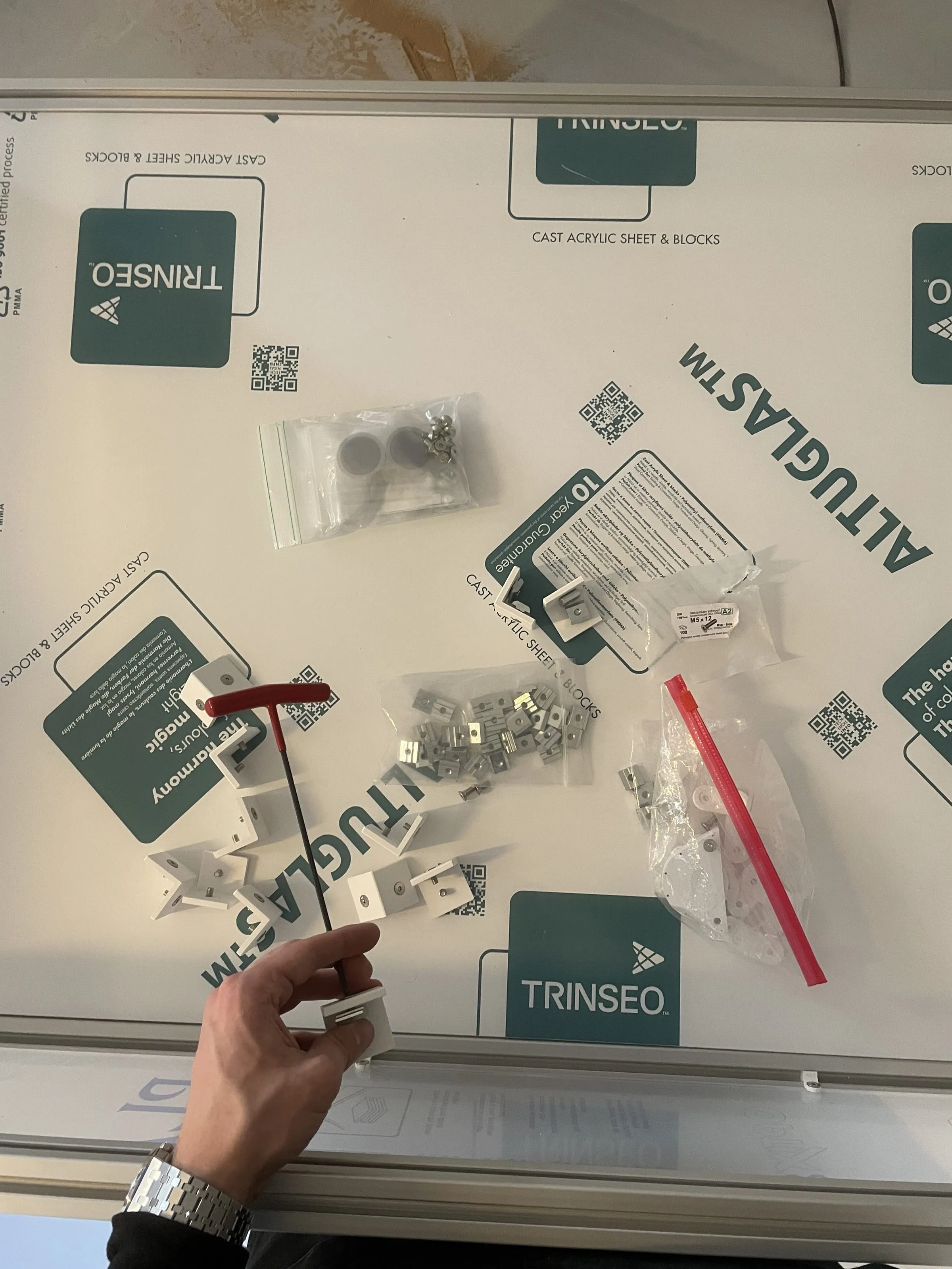 Hand assembling small parts on a sheet of acrylic glass, Analogue store Zeedijk